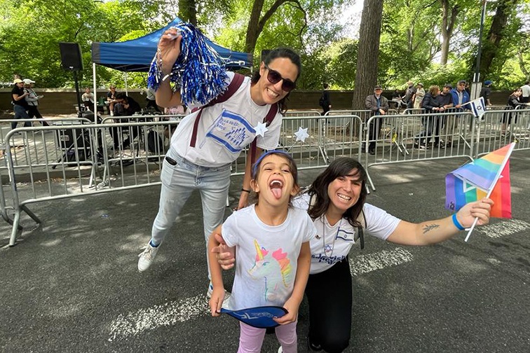 Liana holds a Pride flag next to her partner and son