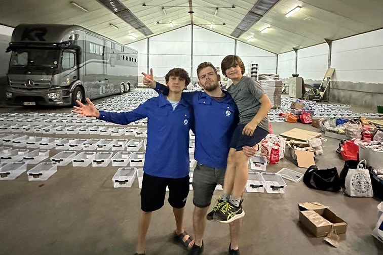 Harel, middle, The Jewish Agency's Israeli emissary in Belgium, stands with community members among boxes they are packing with equipment for Israeli soldiers