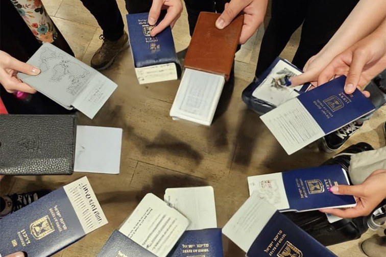 Ella and other Shlichim and camp staff hold up their passports and tickets